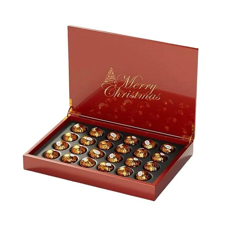 Luxuosa caixa de chocolate em madeira vermelha com uma gravação "Merry Christmas", com uma tampa transparente e chocolates variados no interior.
