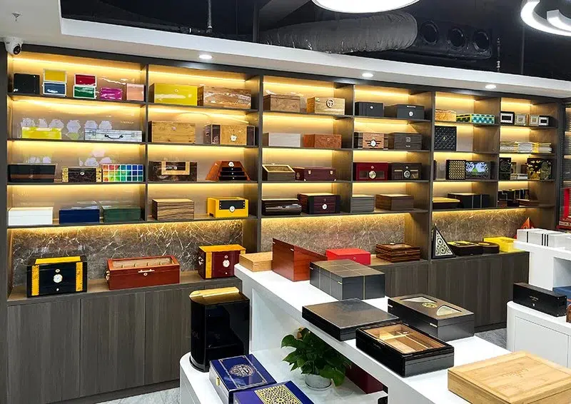 Ein gut beleuchteter Ausstellungsraum mit einer Vielzahl von Mustern luxuriöser Holzkisten, in denen Handwerkskunst und Designoptionen präsentiert werden.