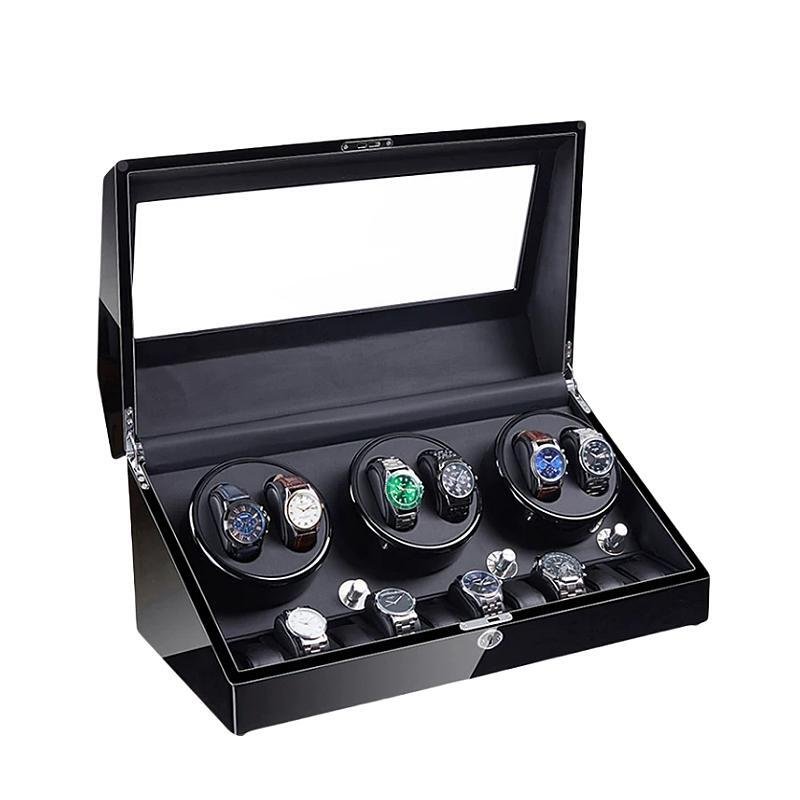 Black wooden watch winder box with a transparent glass lid, rotating compartments, and additional slots for storage.