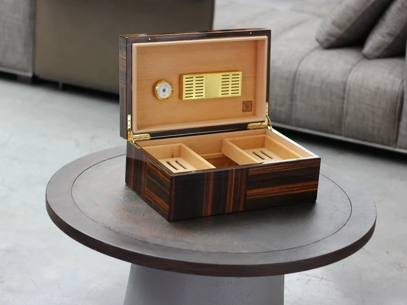 Open wood cigar humidor with gold hygrometer on table