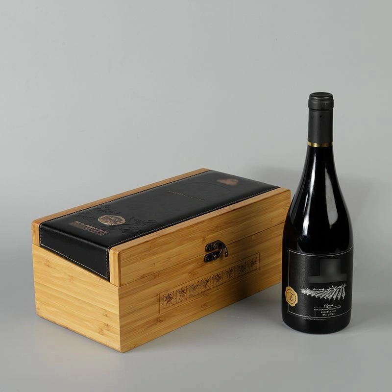 Bamboo whisky box with black leather top and decorative clasp, next to a bottle